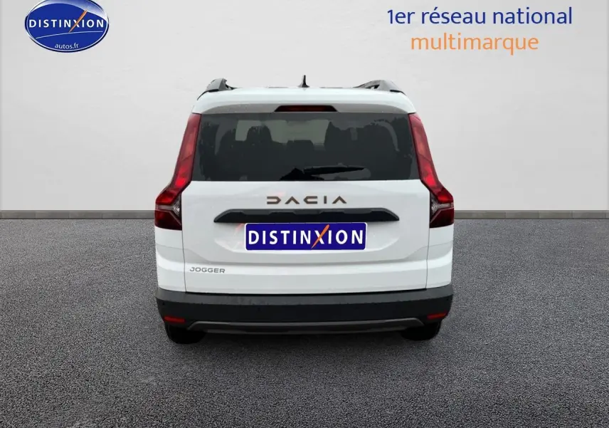Vue arrière d'un Dacia Jogger blanc 2025 avec feux arrière verticaux et barres de toit visibles.