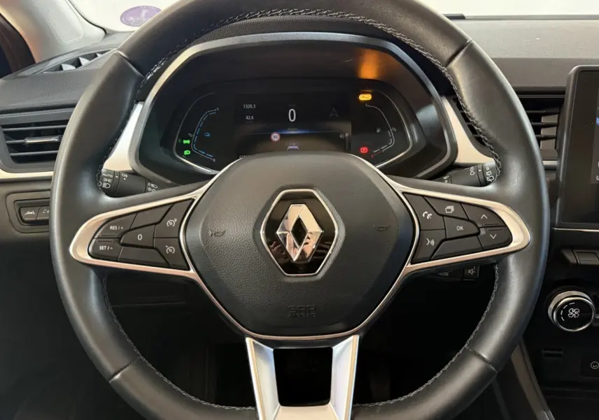 Vue rapprochée du volant en cuir synthétique noir du Renault Captur 2024 avec commandes multifonctions et tableau de bord numérique.