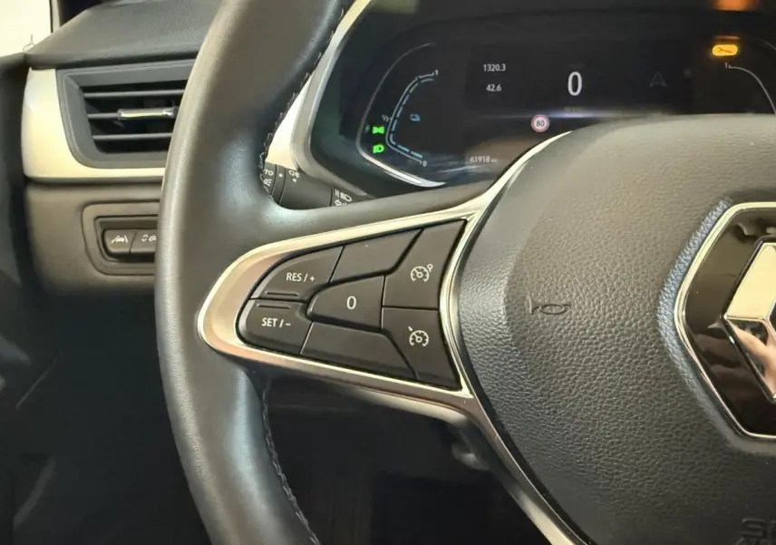 Gros plan sur le volant cuir synthétique noir du Renault Captur 2024 avec commandes multifonctions et tableau de bord numérique.