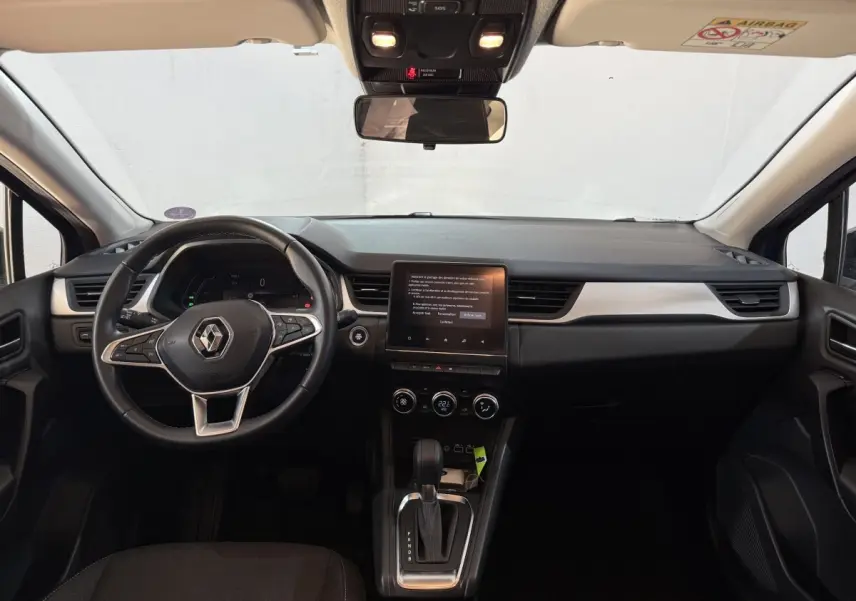 Vue intérieure avant du tableau de bord noir et volant cuir synthétique du Renault Captur bleu 2024 full hybrid.