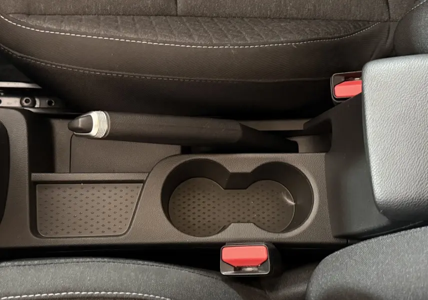 Vue plongeante sur la console centrale noire du Renault Captur 2024 avec frein à main manuel et porte-gobelets.