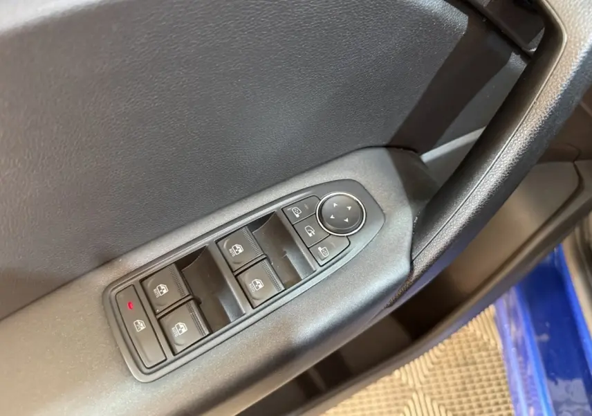 Gros plan sur la commande des vitres côté conducteur du Renault Captur bleu, avec boutons de réglage des rétroviseurs.