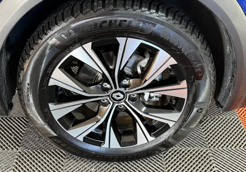 Gros plan sur la roue avant droite du Renault Captur bleu 2024 avec jante alliage bicolore et pneu Michelin.