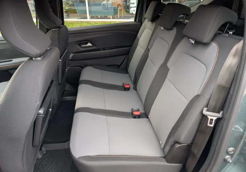 Vue latérale droite de la banquette arrière grise et noire du Dacia Jogger 2025 avec surpiqûres brun cuivré et ceintures de sécurité.