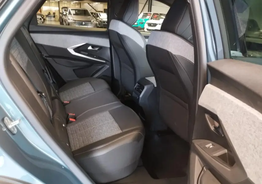 Vue côté gauche arrière de l’habitacle du Peugeot 3008 bleu Azul, sièges tissu gris et noir avec surpiqûres claires.