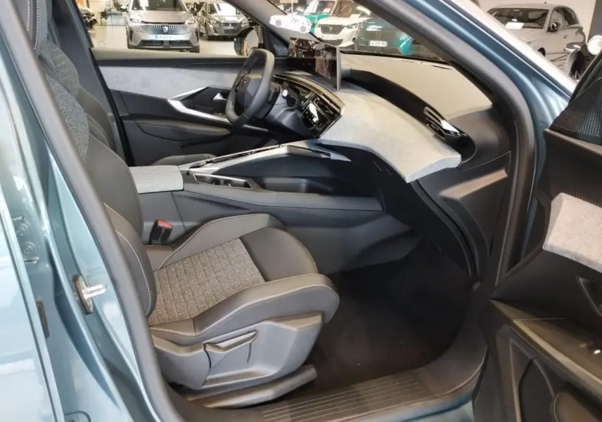 Vue intérieure côté passager avant du Peugeot 3008 Bleu Azul 2025 avec tableau de bord tissu clair et écran incurvé flottant.