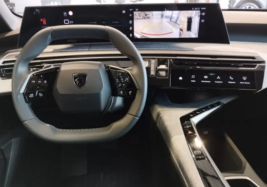 Vue intérieure du tableau de bord du Peugeot 3008 2025 avec volant compact et double écran HD incurvé flottant.