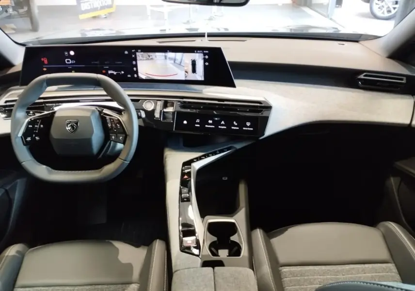 Vue intérieure avant du Peugeot 3008 2025, tableau de bord avec double écran incurvé et volant compact noir.