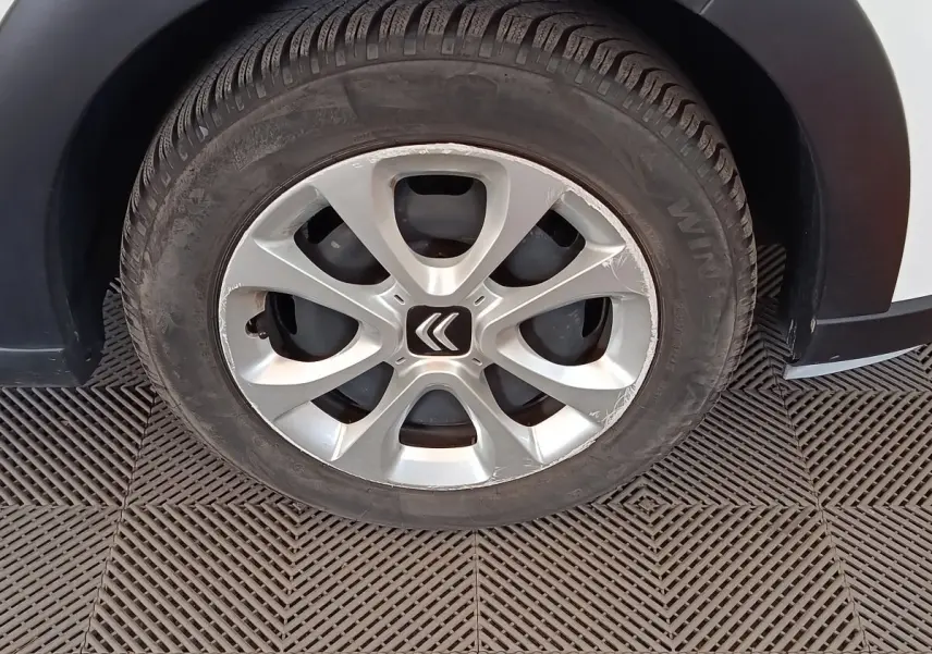 Gros plan sur la roue avant gauche d'une Citroën C3 blanche de 2020 avec jante alliage et logo Citroën central.