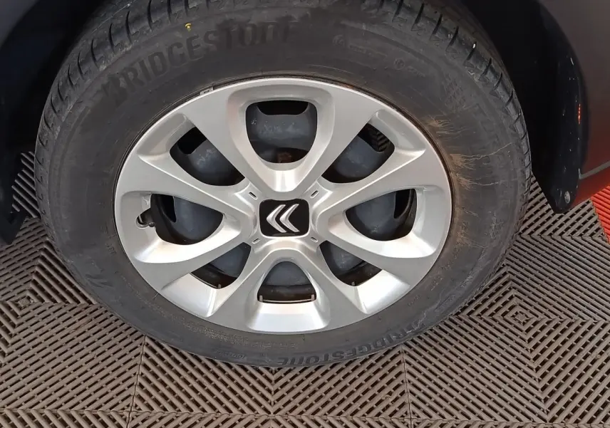 Gros plan sur la roue avant gauche d'une Citroën C3 blanche avec jante alliage et logo Citroën central.