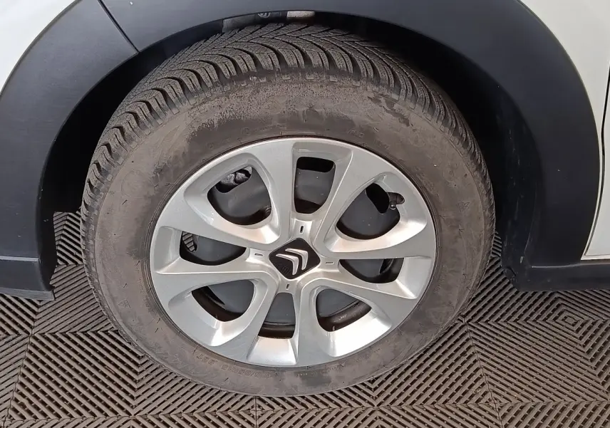 Gros plan sur la roue avant droite d'une Citroën C3 blanche avec jante argentée et logo Citroën au centre.