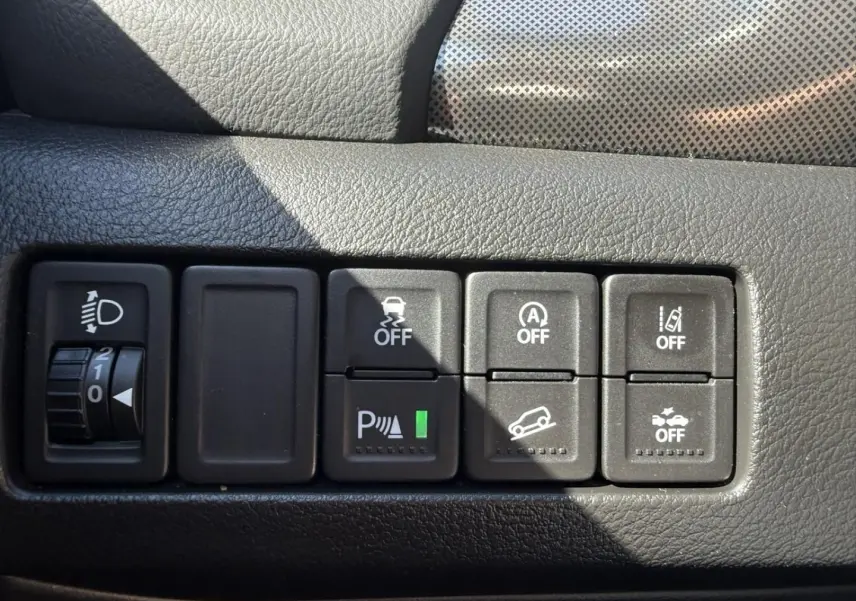 Gros plan sur les commandes de sécurité et assistance du tableau de bord du Suzuki Vitara 2025, intérieur noir texturé.