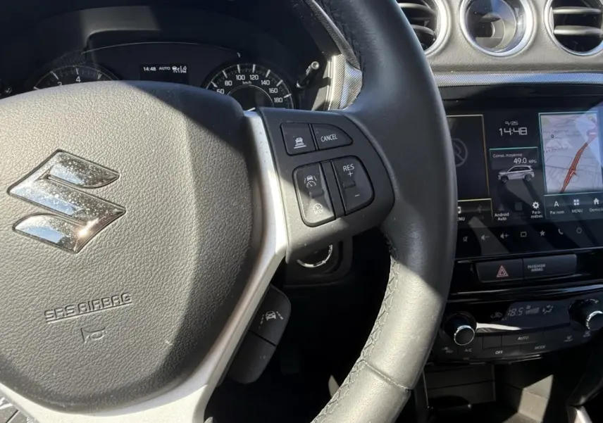 Vue rapprochée du volant et tableau de bord du Suzuki Vitara 2025, avec commandes au volant et écran tactile visible.