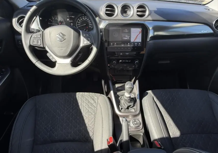 Vue intérieure avant du Suzuki Vitara 2025 bleu foncé, volant multifonction, boîte manuelle et écran tactile central.
