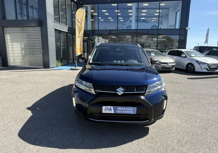 Vue avant d'un Suzuki Vitara 2025 bleu foncé métal, avec calandre noire et logo Suzuki bien visible.