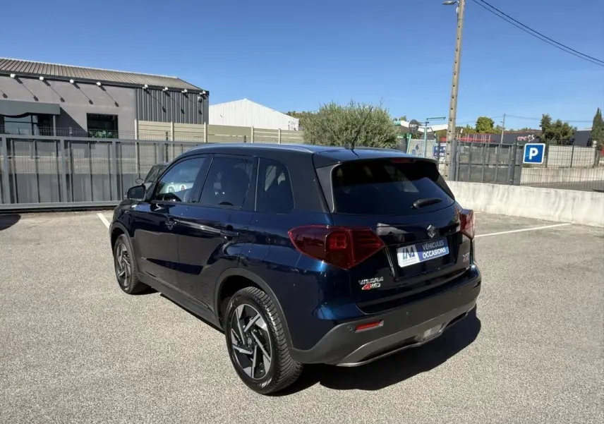 Suzuki Vitara 2025 bleu foncé métal en 3/4 arrière droit, avec jantes alliage et toit noir contrasté.