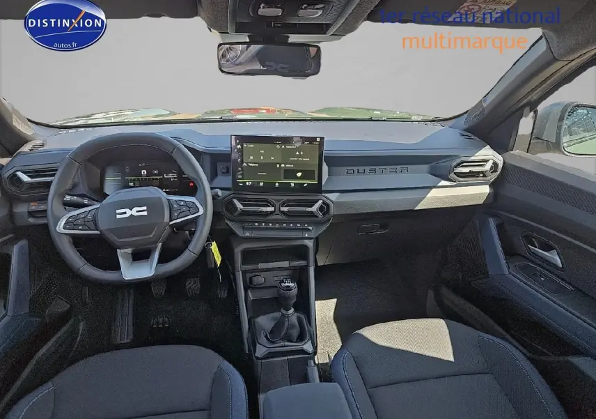Intérieur avant du Dacia Duster 2025 avec tableau de bord moderne, volant multifonction et écran tactile central.