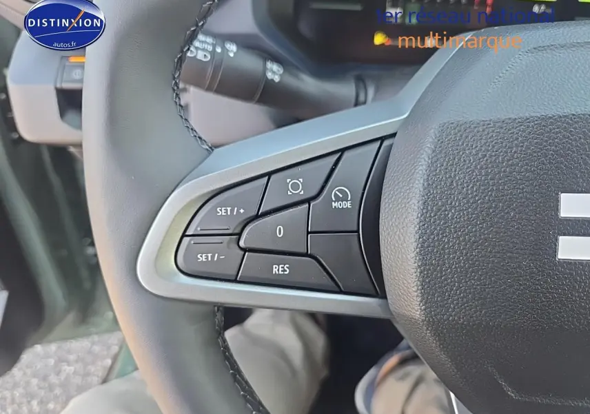 Gros plan sur les commandes à gauche du volant du Dacia Duster vert kaki 2025, avec boutons multifonctions visibles.