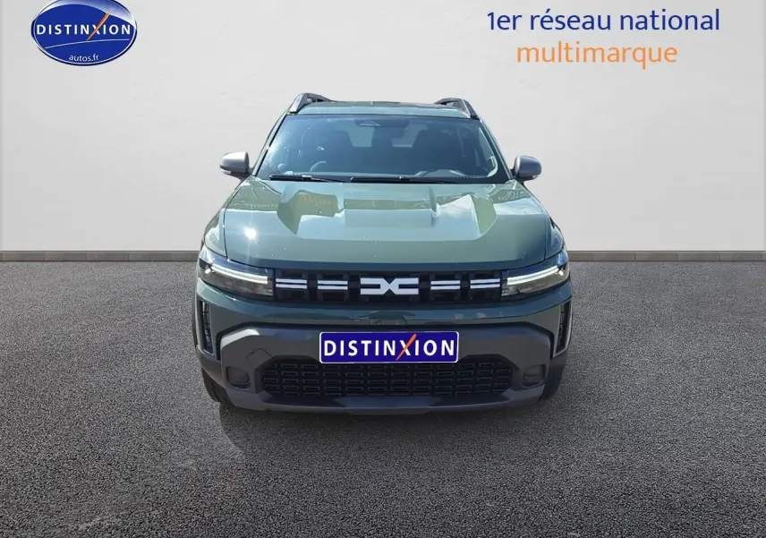 Vue avant d'un Dacia Duster 2025 vert kaki avec calandre moderne et barres de toit visibles.