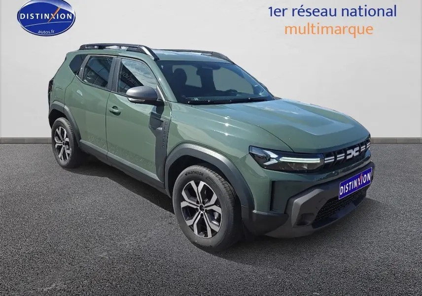 Dacia Duster vert kaki en 3/4 avant droit, avec jantes alu et barres de toit visibles sur fond neutre.