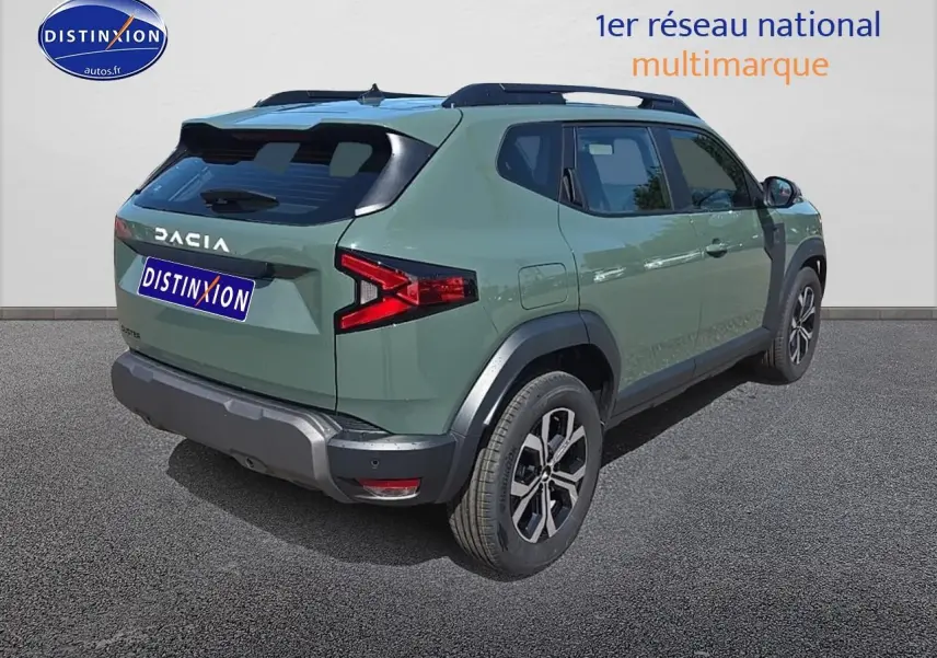 Vue 3/4 arrière droite du Dacia Duster 2025 vert kaki avec barres de toit et jantes alu distinctives.