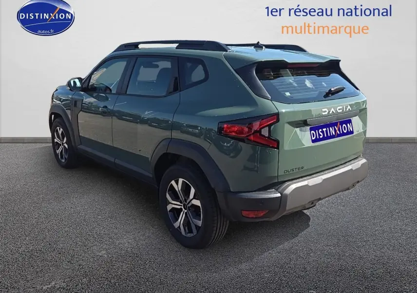 Vue 3/4 arrière droite d'un Dacia Duster vert kaki avec barres de toit et jantes alu sur fond neutre.