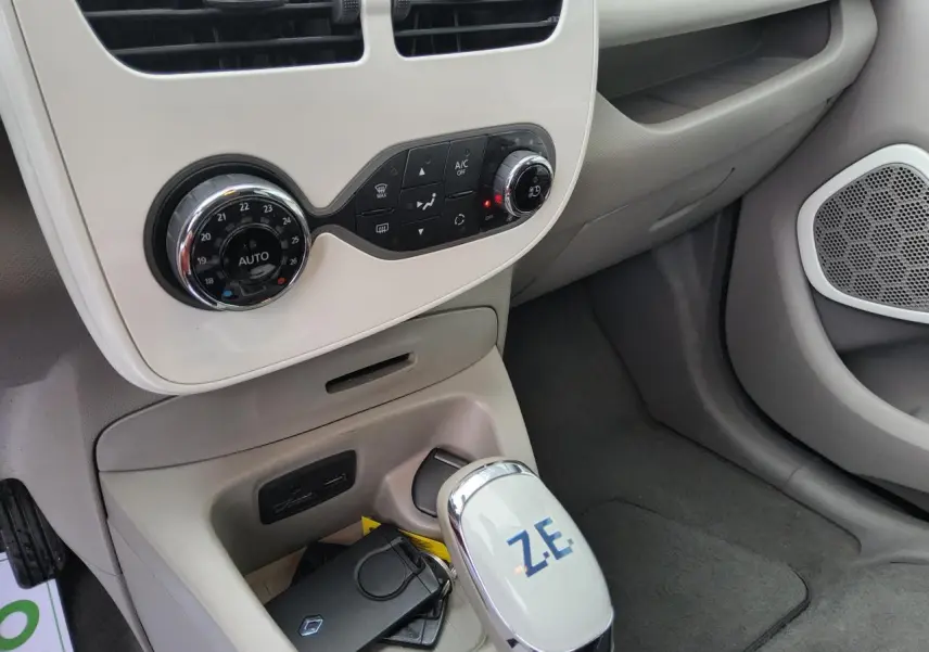 Gros plan sur la console centrale beige de la Renault ZOE blanche, avec levier de vitesse marqué Z.E. et commandes climatisation.