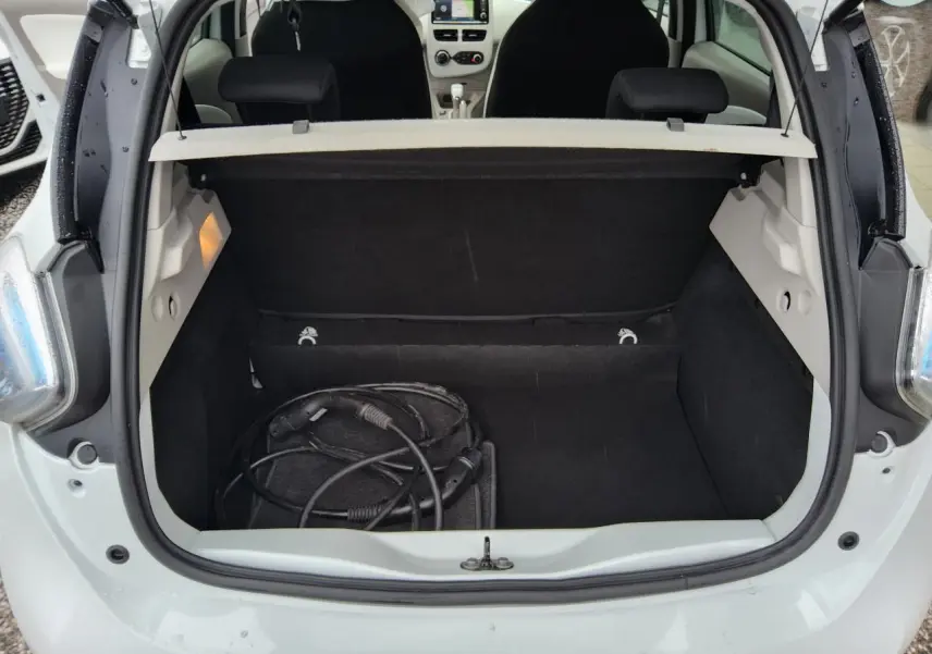 Coffre ouvert d'une Renault ZOE blanche vue arrière, avec câble de recharge électrique visible à l'intérieur.