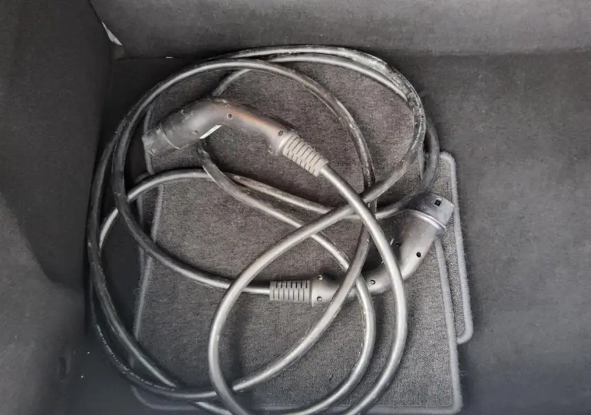 Câble de recharge électrique noir enroulé dans le coffre d'une Renault ZOE blanche Z.E. R240 Life 2016.