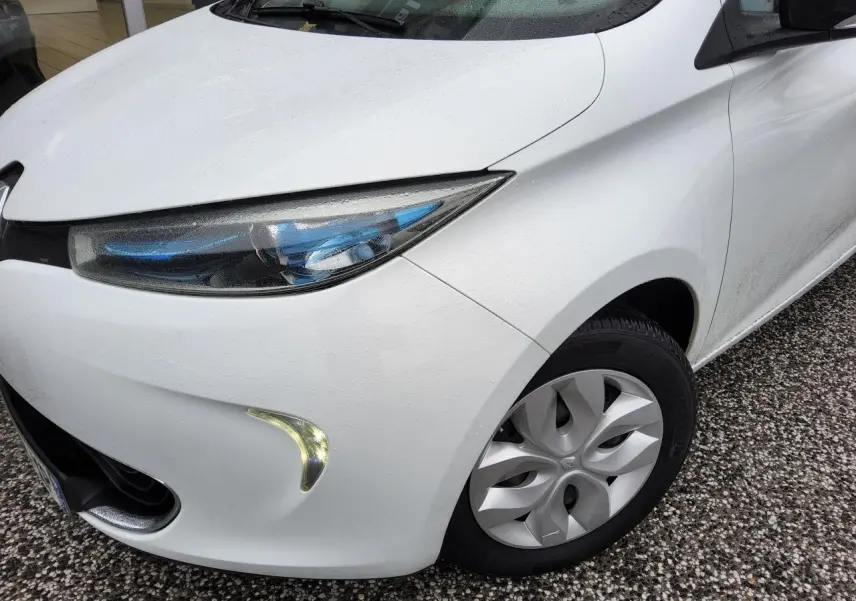 Vue 3/4 avant droit d'une Renault ZOE blanche avec phares à LED bleutés et enjoliveurs 15 pouces.