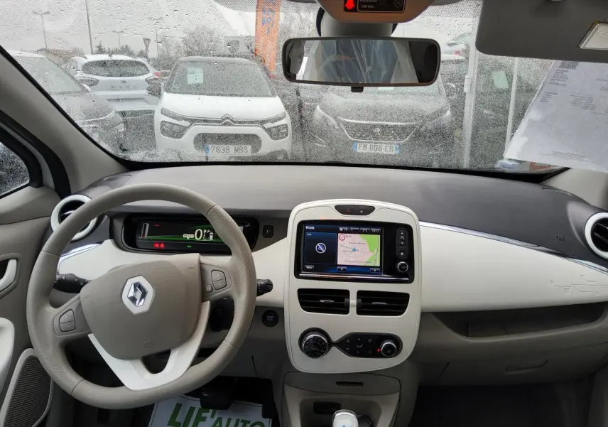 Vue intérieure frontale du tableau de bord beige et noir de la Renault ZOE Z.E. R240 Life avec écran tactile et volant multifonction.