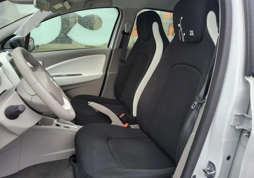 Intérieur de la Renault ZOE blanche vue côté gauche, sièges noirs avec logo Z.E. sur l'appuie-tête conducteur.