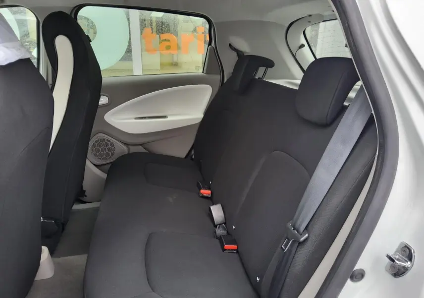 Vue intérieure côté droit sur la banquette arrière noire de la Renault ZOE blanche, avec appuie-têtes réglables.