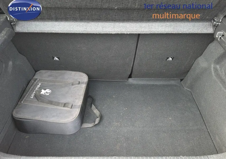 Coffre ouvert d'une Peugeot 208 électrique jaune Faro métal, montrant un sac Peugeot noir rangé à gauche.