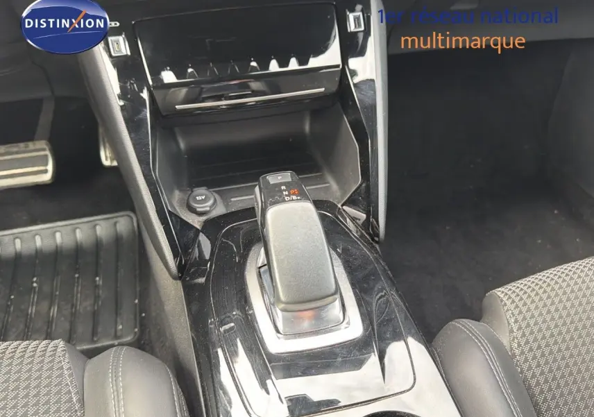 Le levier de vitesses automatique noir brillant au centre de la console d'une Peugeot 208 électrique, vue intérieure rapprochée.