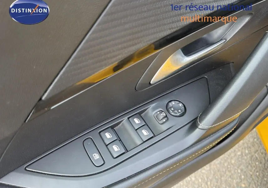 Gros plan sur la commande des vitres côté conducteur d'une Peugeot 208 électrique jaune Faro avec intérieur noir.