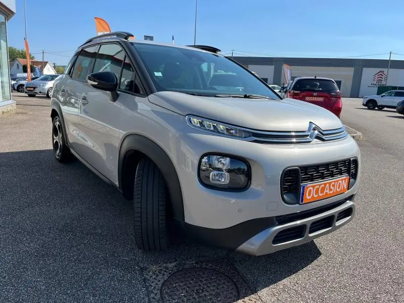 Citroën C3 Aircross BlueHDi 100ch Shine sable vue 3/4 avant avec toit et rétroviseurs noirs sur parking