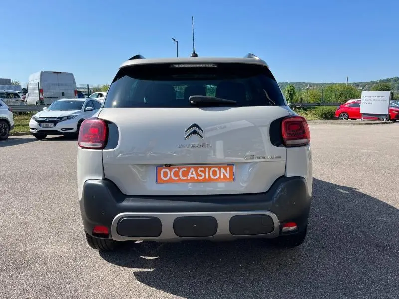 Vue arrière d'une Citroën C3 Aircross sable avec détails noirs et plaque orange "OCCASION" sur un parking extérieur.