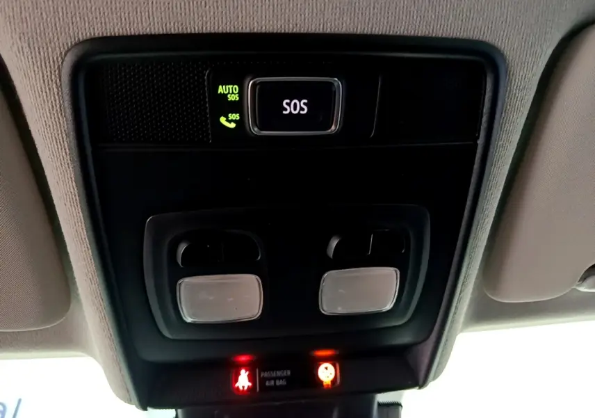 Vue rapprochée du plafonnier intérieur noir avec bouton SOS éclairé et voyants de sécurité rouges dans une Renault Clio gris foncé.