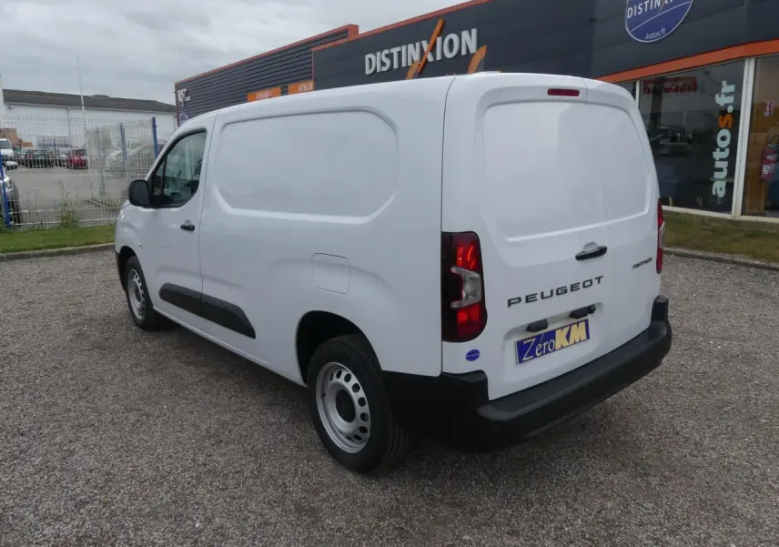 Vue 3/4 arrière droite d’un Peugeot Partner blanc 2025 avec porte latérale coulissante et jantes tôles grises.