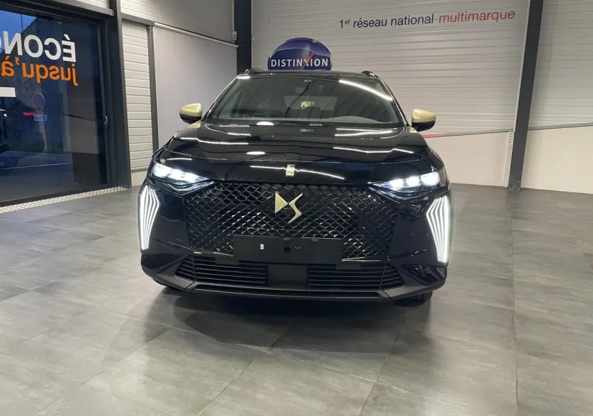 Vue avant d'un DS7 Crossback noir métallisé avec calandre DS Wings et feux LED verticaux allumés en showroom.