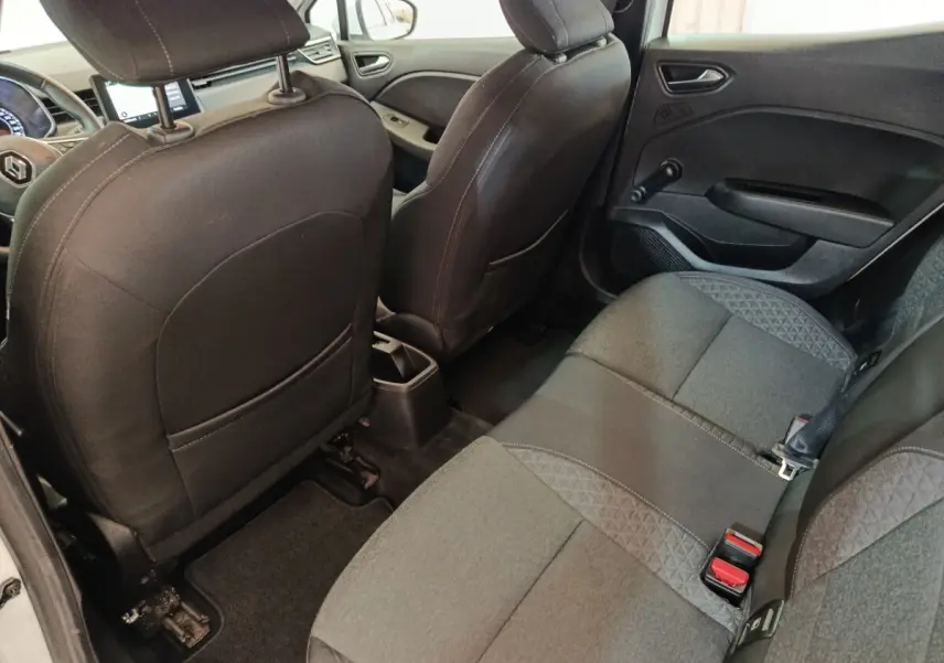 Vue intérieure arrière côté droit de la Renault Clio Business blanche, montrant la banquette tissu gris et les dossiers des sièges avant noirs.