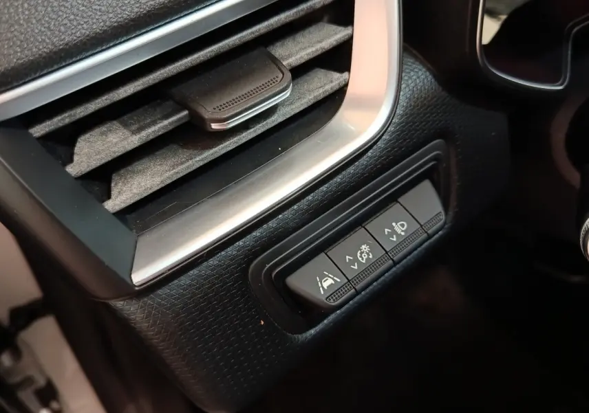 Détail intérieur du tableau de bord de la Renault Clio Business blanc, avec commandes d'assistance et réglage phares.