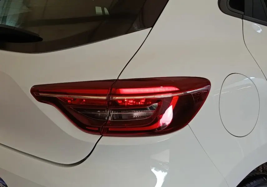 Gros plan sur le feu arrière droit d’une Renault Clio blanche de 2021, avec la trappe à carburant visible.