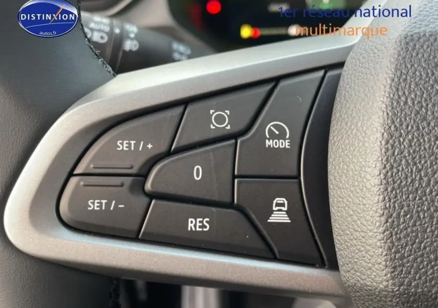 Gros plan sur les commandes au volant à gauche du Dacia Bigster gris schiste métal, montrant les boutons de régulateur de vitesse.