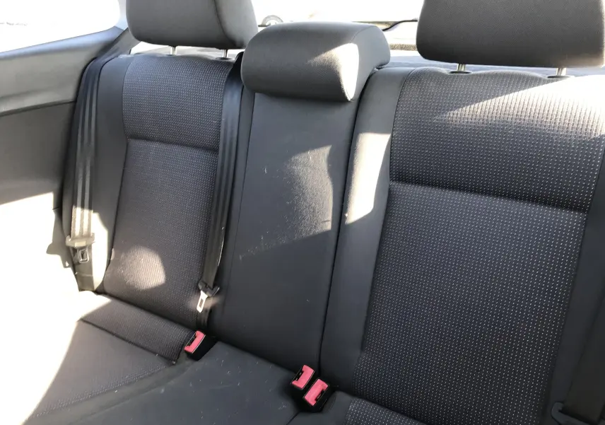 Vue rapprochée des sièges arrière en tissu noir de la Volkswagen Polo Match gris argent de 2004, avec ceintures de sécurité visibles.