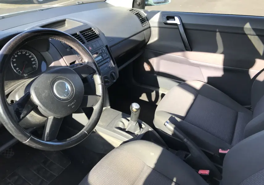 Intérieur avant droit d'une Volkswagen Polo Match 2004 avec volant noir, sièges tissu noir et levier de vitesse manuel.