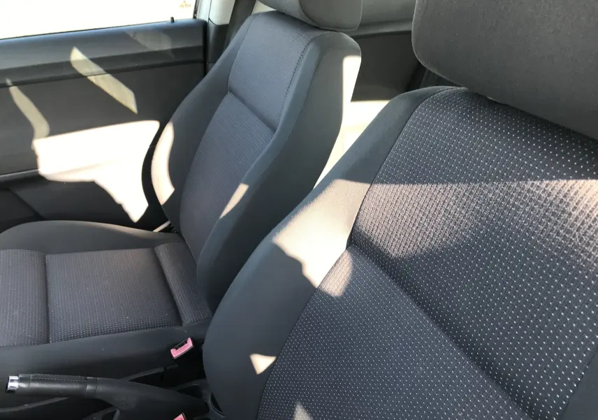 Gros plan sur les sièges avant en tissu noir de la Volkswagen Polo Match 2004, ambiance intérieure lumineuse.