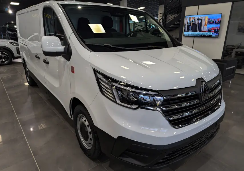 Renault Trafic Fourgon blanc minéral vu en 3/4 avant droit, avec calandre chromée et phares LED modernes.