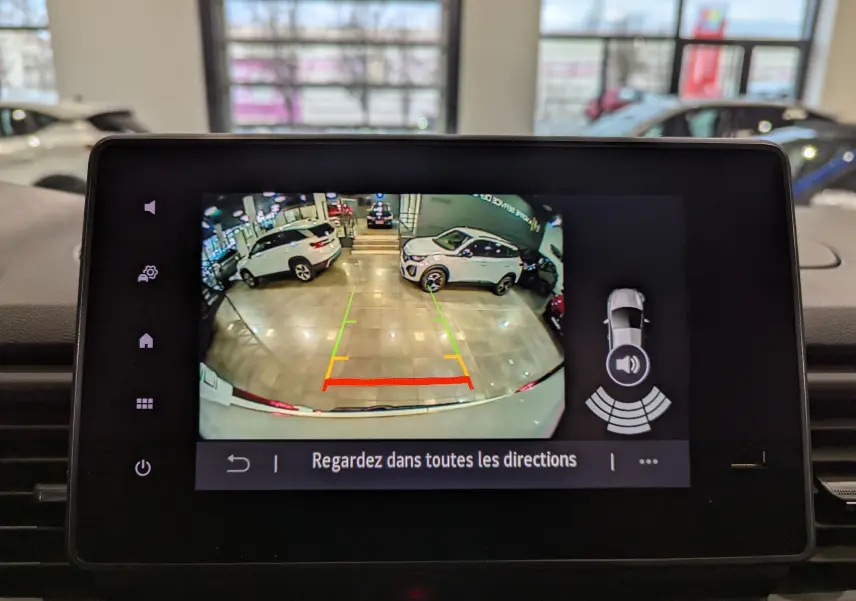 Affichage de la caméra de recul du Renault Trafic Fourgon blanc minéral, avec lignes de guidage et alertes de proximité visibles.